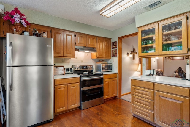 kitchen with backsplash, dark hardwood / wood-style flooring, stainless steel appliances, and a textured ceiling