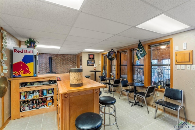 bar featuring butcher block counters, a drop ceiling, and light tile patterned floors