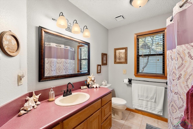 bathroom with tile patterned floors, vanity, a textured ceiling, and toilet