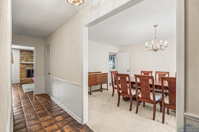 dining room featuring a textured ceiling, a notable chandelier, and a fireplace