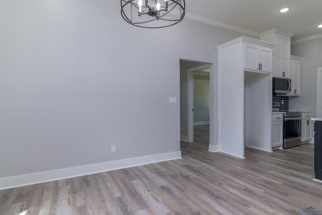 kitchen featuring backsplash, crown molding, white cabinets, and appliances with stainless steel finishes