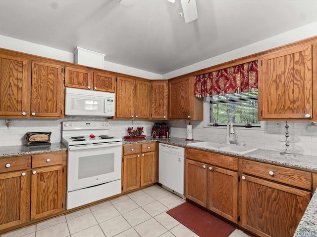 kitchen with white appliances, backsplash, sink, light tile patterned floors, and light stone counters