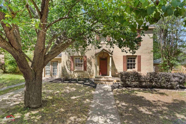 view of property hidden behind natural elements featuring brick siding