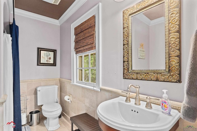 bathroom with crown molding, toilet, tile walls, and a sink