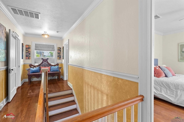 corridor featuring visible vents, crown molding, and wood finished floors