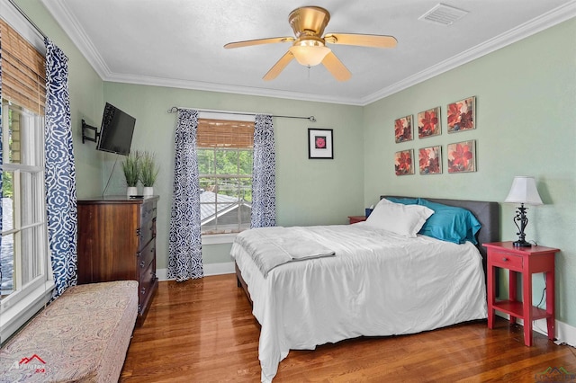 bedroom with visible vents, baseboards, crown molding, and wood finished floors