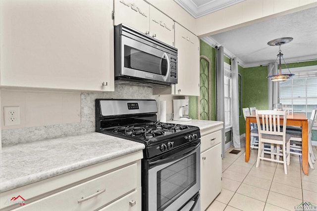 kitchen with crown molding, stainless steel appliances, light tile patterned floors, and light countertops