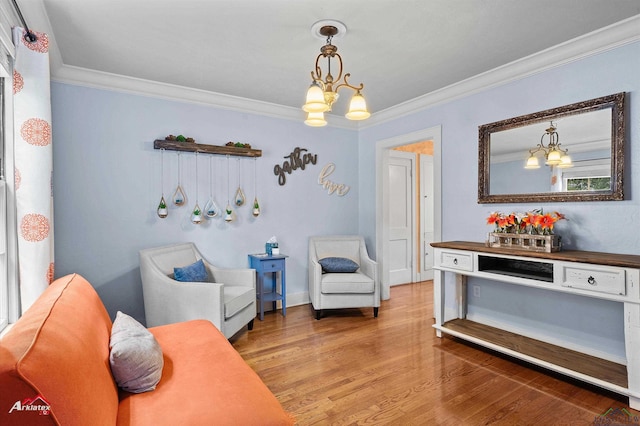 sitting room featuring crown molding, wood finished floors, and a chandelier