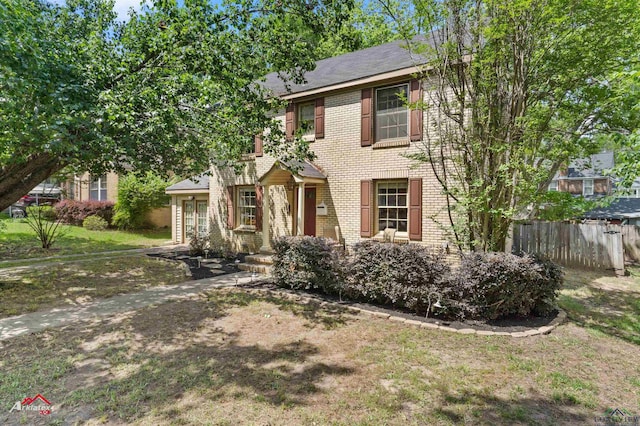 colonial-style house featuring brick siding and fence