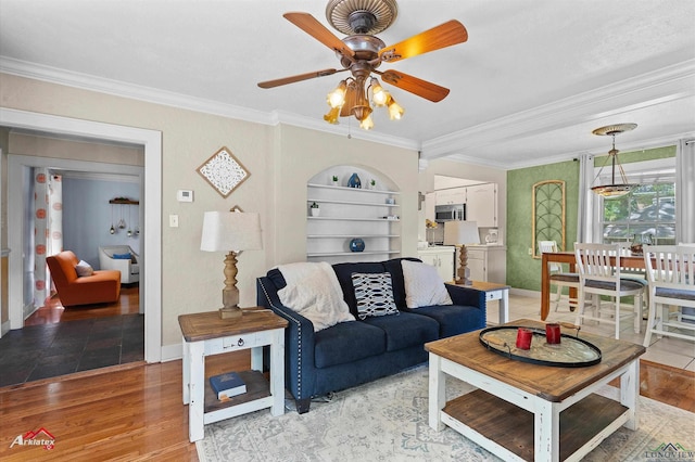 living area with baseboards, ornamental molding, light wood finished floors, and a ceiling fan