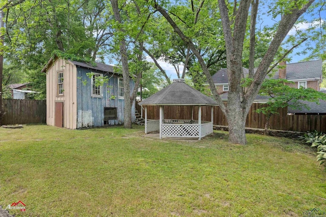 exterior space with an outdoor structure, a gazebo, a fenced backyard, and a storage unit