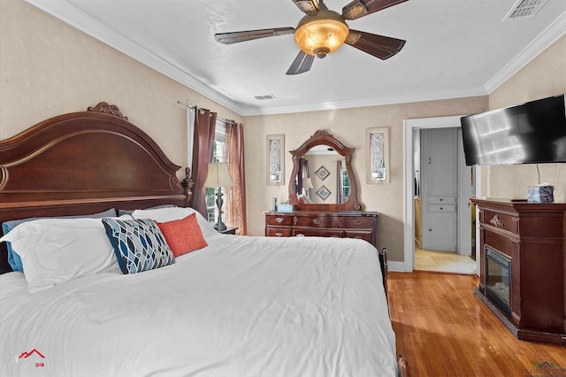 bedroom with ceiling fan, ornamental molding, wood finished floors, and visible vents