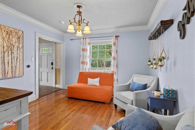 living area featuring baseboards, ornamental molding, wood finished floors, and a chandelier