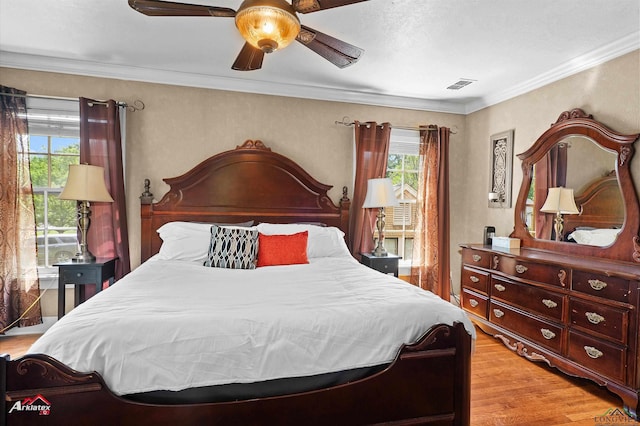 bedroom featuring ornamental molding, a ceiling fan, light wood-style flooring, and visible vents