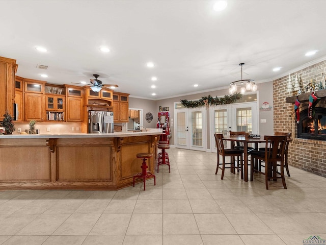 kitchen with crown molding, ceiling fan, hanging light fixtures, stainless steel refrigerator with ice dispenser, and kitchen peninsula