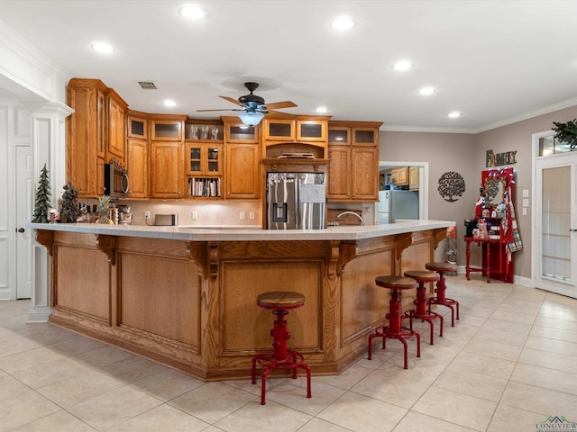 kitchen featuring crown molding, a kitchen breakfast bar, ceiling fan, and appliances with stainless steel finishes