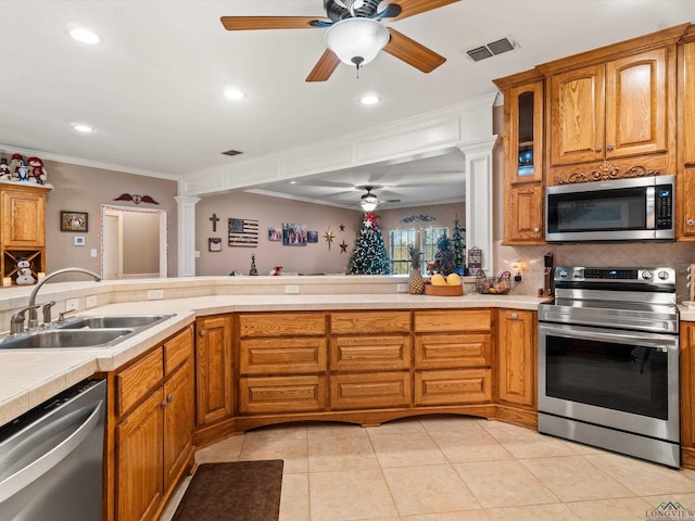 kitchen featuring sink, ornamental molding, appliances with stainless steel finishes, decorative columns, and backsplash