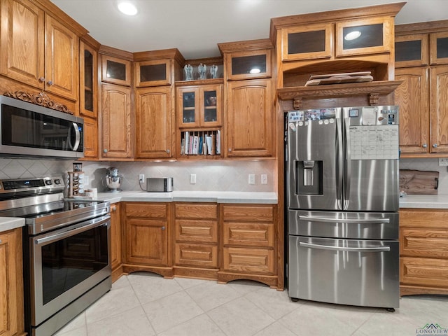 kitchen with appliances with stainless steel finishes, light tile patterned floors, and backsplash