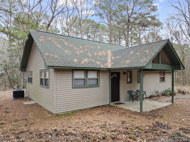 chalet / cabin featuring a shingled roof, a patio area, and cooling unit