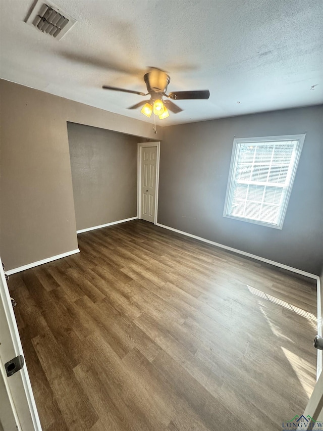 empty room featuring ceiling fan, wood-type flooring, and a textured ceiling