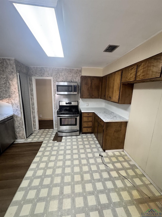 kitchen featuring dark brown cabinetry, stainless steel appliances, and a skylight