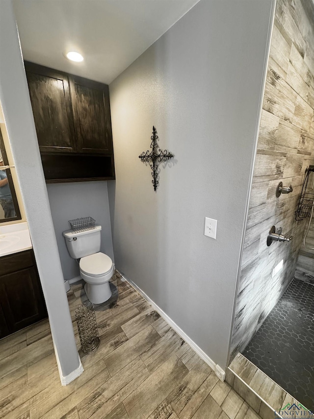 bathroom featuring a tile shower, vanity, and toilet