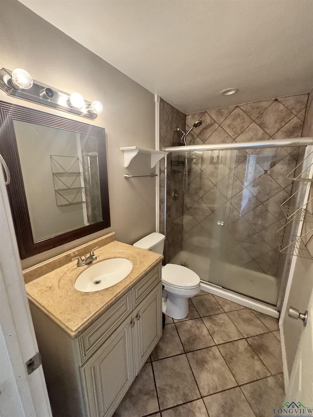 bathroom with tile patterned flooring, vanity, an enclosed shower, and toilet