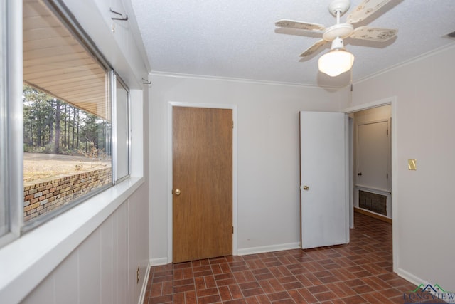 unfurnished room with ceiling fan, ornamental molding, and a textured ceiling