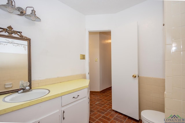 bathroom with tile walls, vanity, and toilet