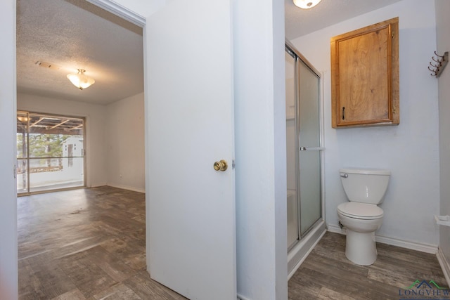 bathroom featuring a shower with door, hardwood / wood-style flooring, and toilet