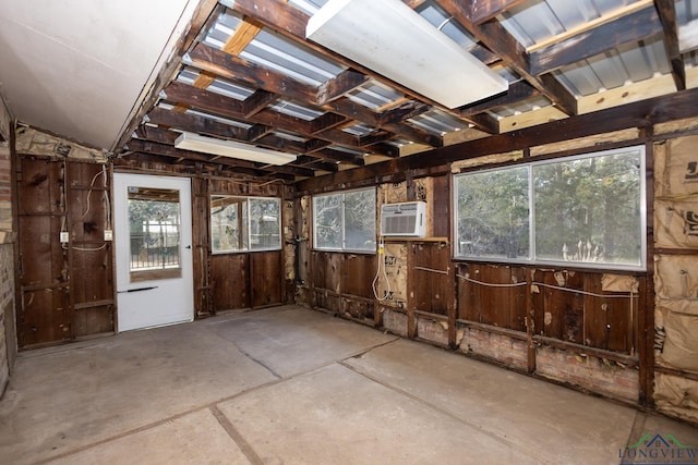 misc room featuring wooden walls, concrete flooring, and a wall mounted AC