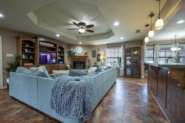 living room featuring ceiling fan and a tray ceiling