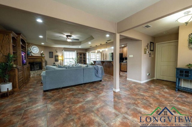 unfurnished living room featuring ceiling fan and a raised ceiling