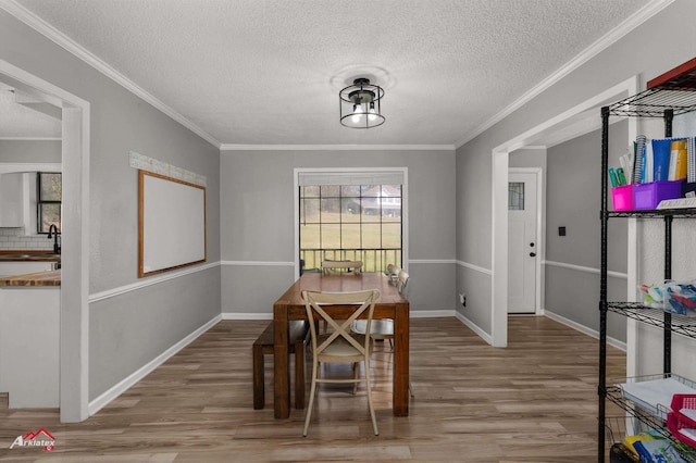 dining area featuring ornamental molding, wood finished floors, and a healthy amount of sunlight