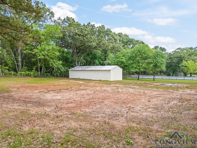 view of yard with fence, a pole building, and an outbuilding