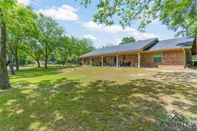 rear view of property featuring a lawn, central AC, and brick siding