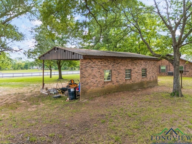 view of side of property featuring a yard, brick siding, fence, and central air condition unit