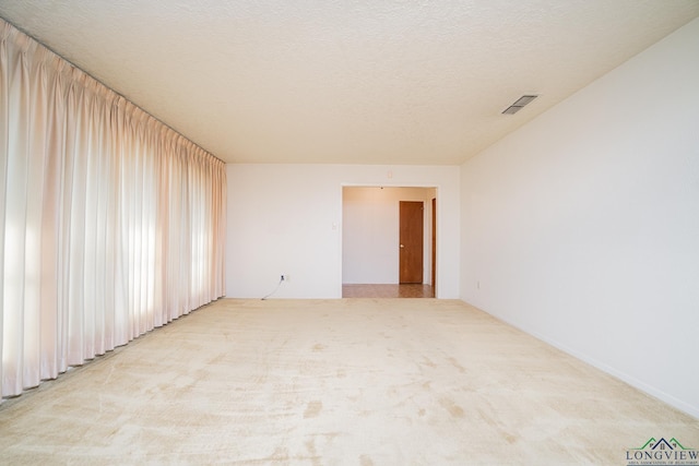 unfurnished room with a textured ceiling and light colored carpet