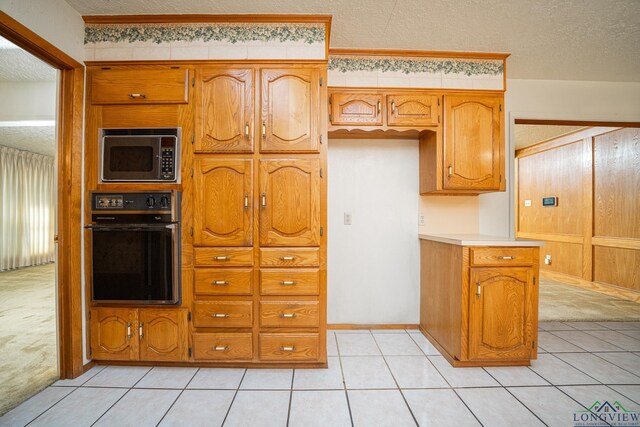 kitchen featuring light carpet, black appliances, and a textured ceiling