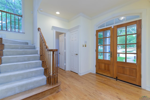 foyer with french doors, light hardwood / wood-style floors, and crown molding