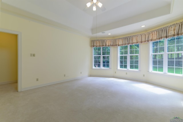 empty room featuring carpet flooring, ceiling fan, and a raised ceiling