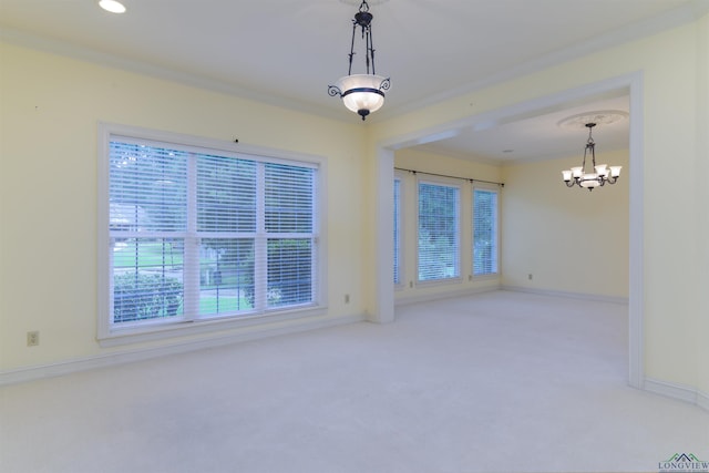 carpeted spare room with a chandelier, a healthy amount of sunlight, and ornamental molding