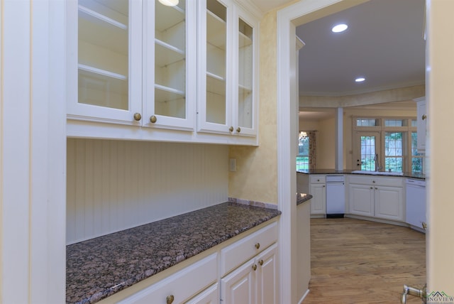 interior space with dishwasher, dark stone counters, sink, light hardwood / wood-style flooring, and white cabinetry