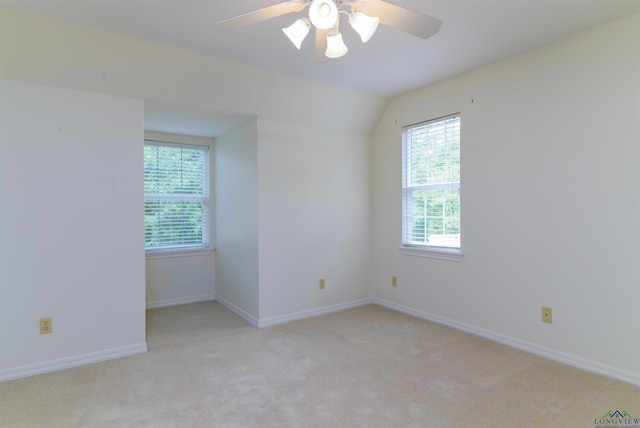 spare room featuring ceiling fan, light colored carpet, and vaulted ceiling