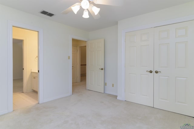 unfurnished bedroom featuring connected bathroom, ceiling fan, a closet, and light colored carpet