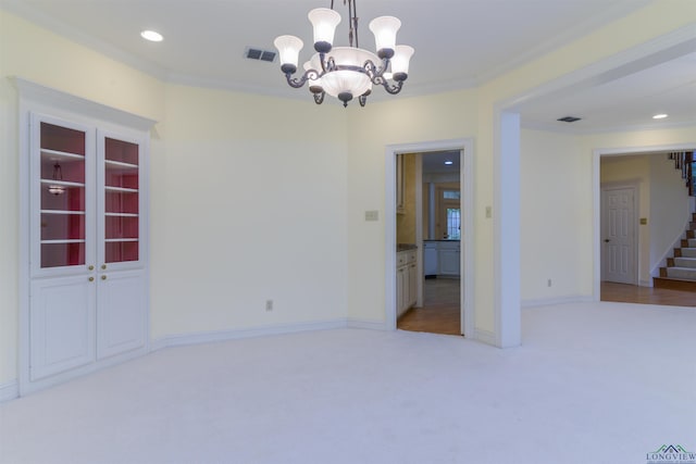 spare room featuring a chandelier, light colored carpet, and ornamental molding