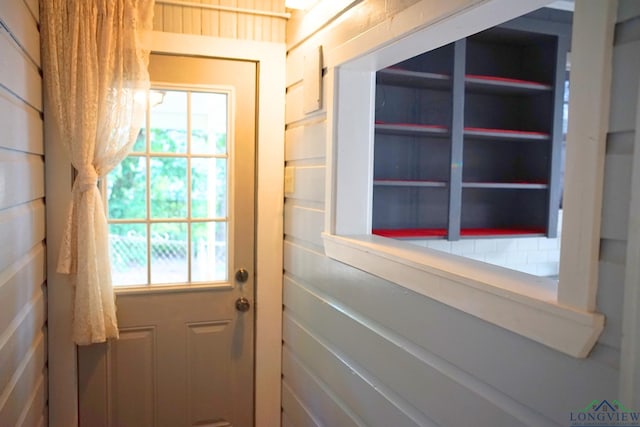 doorway to outside with wooden walls