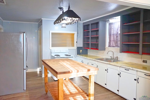 kitchen with white cabinetry, sink, crown molding, refrigerator, and pendant lighting