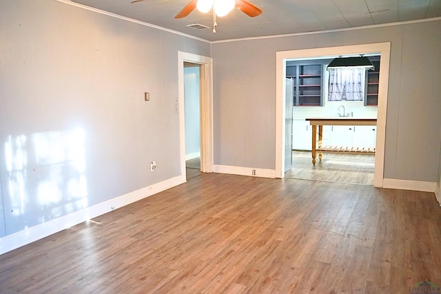 empty room with hardwood / wood-style flooring, sink, ceiling fan, and ornamental molding