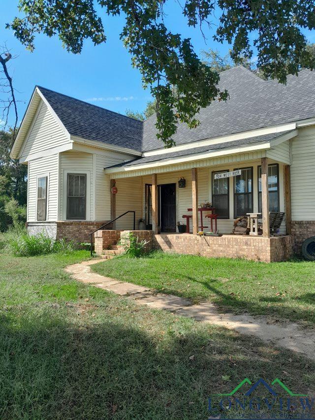 back of property featuring a yard and covered porch